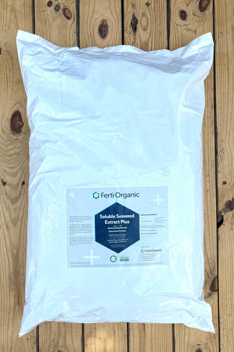 A large white plastic bag of Ferti Organic Soluble Seaweed Extract Plus, placed flat on a light brown wooden plank surface.