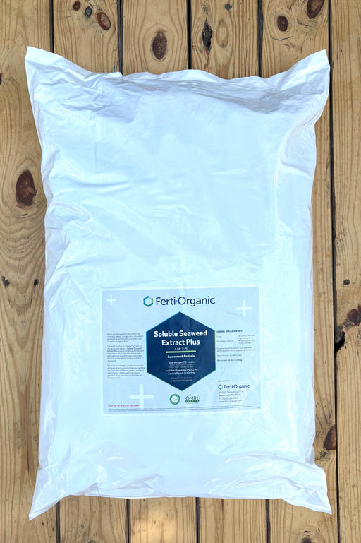 A large white plastic bag of Ferti Organic Soluble Seaweed Extract Plus, placed flat on a light brown wooden plank surface.