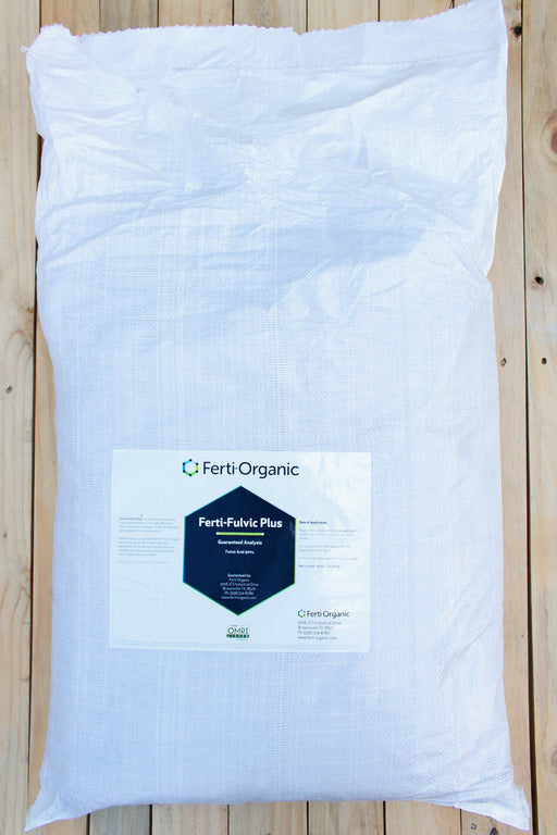 A large white plastic bag of Ferti-Organic Ferti-Fulvic Plus organic fertilizer, displayed flat on a light-colored wooden plank surface.