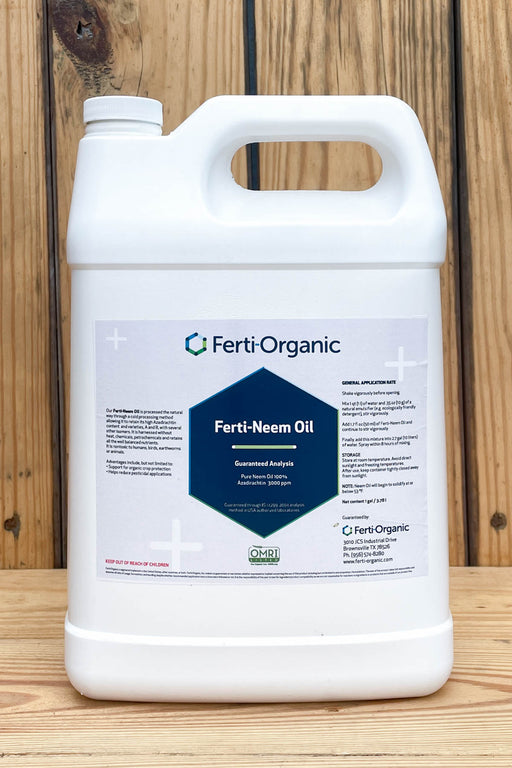 A white plastic jug of Ferti-Organic Ferti-Neem Oil standing on a wooden surface against a wooden plank background.