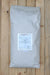 A large white paper bag with a white label reading 'Grandevo WDG' lies on a light-colored wooden plank surface.
