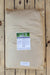 A large brown paper bag of Grower's Secret with a white and green label, placed on a light-colored wooden plank surface.