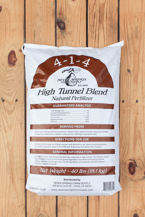 A 40 lb bag of Seven Springs Farm Supply 4-1-4 High Tunnel Blend Natural Fertilizer, displayed flat on a light brown wooden plank background.