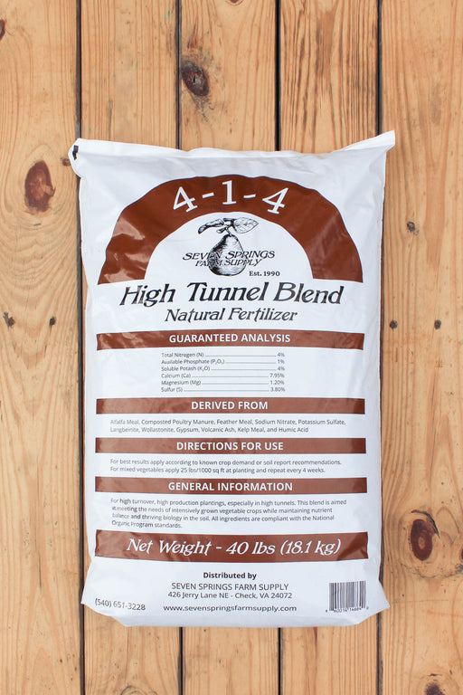 A 40 lb bag of Seven Springs Farm Supply 4-1-4 High Tunnel Blend Natural Fertilizer, displayed flat on a light brown wooden plank background.