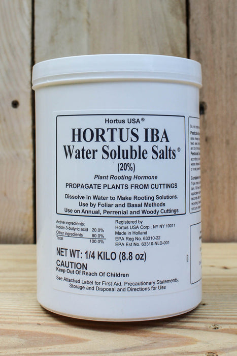 A white plastic tub of Hortus IBA Water Soluble Salts (20%) plant rooting hormone, displayed on a light-colored wooden plank background.