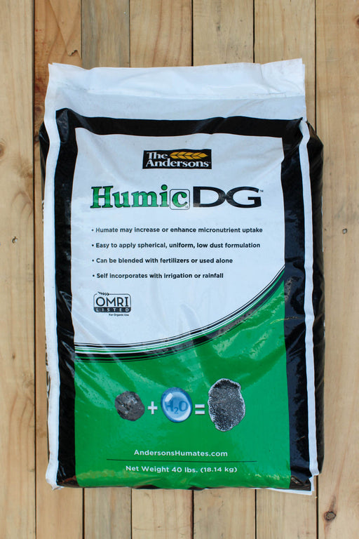 A 40 lb bag of The Andersons Humic DG soil supplement, displayed flat on a light-colored wooden plank surface. The packaging is white with black borders and a green lower section, featuring the product name 'Humic DG' in green and black text.