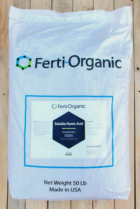 A 50 lb white bag of Ferti-Organic Soluble Humic Acid, displayed flat on a light-colored wooden plank surface. The packaging features the Ferti-Organic brand name and logo, with product details printed at the bottom.