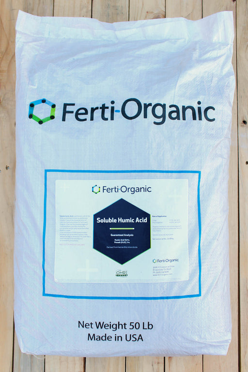 A 50 lb white bag of Ferti-Organic Soluble Humic Acid, displayed flat on a light-colored wooden plank surface. The packaging features the Ferti-Organic brand name and logo, with product details printed at the bottom.