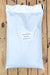 A large white plastic bag of coir with a printed label placed on a wooden plank surface.