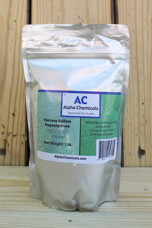 A 1 lb stand-up pouch of Alpha Chemicals Ferrous Sulfate Heptahydrate, displayed on a wooden surface against a wooden plank background.