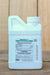 A small white plastic bottle of Madex HP Insecticidal Virus, standing upright on a wooden surface with a blurred wood background.