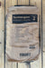 A brown paper bag of Vibrantz Technologies Tecmangam manganese sulfate monohydrate, displayed flat on a light-colored wooden plank surface.