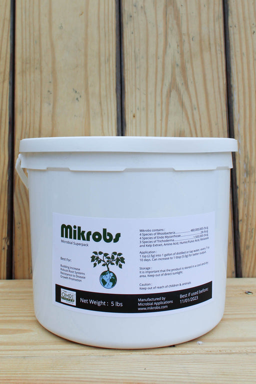 A 5 lb white plastic bucket of Mikrobs, featuring a white label with green and black text, set against a light wood panel background.
