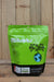 A green stand-up pouch of Mikrob's Microbial Superpack with a black bottom section, photographed against a rustic wooden plank background.