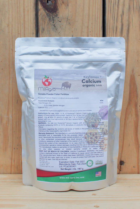 A stand-up pouch of MilAgro Calcium Organic 5-0-0 soluble powder fertilizer, displayed against a rustic wooden plank background.