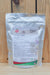 A silver stand-up pouch of MilAgro Keylamax Copper Organic Fertilizer, displayed against a rustic wooden plank background.