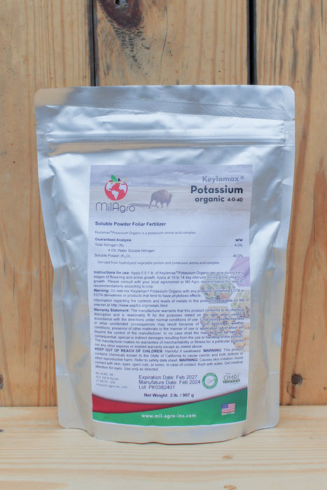 A stand-up pouch of MilAgro Keylamax Organic 4-0-40 Potassium Powder Fertilizer, displayed on a light wood surface against a wooden plank background.
