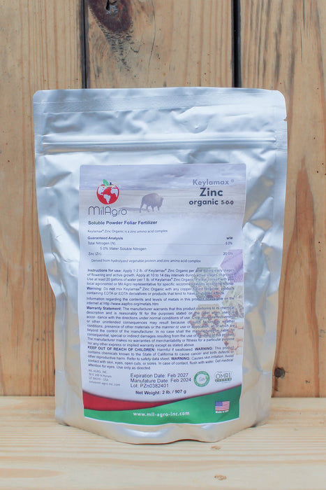 A silver stand-up pouch of MilAgro Keylamax Zinc Organic 5-0-0 Soluble Powder Fertilizer, displayed against a rustic wooden plank background.