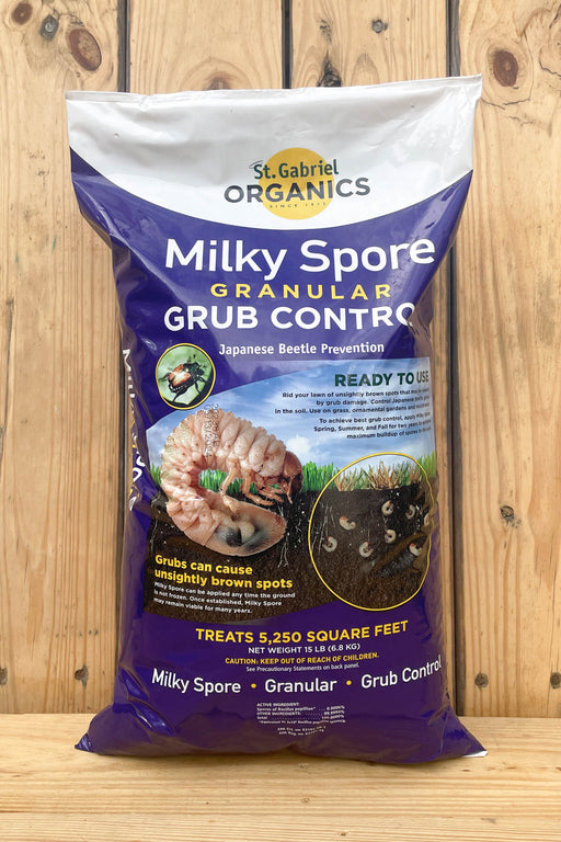 A bag of St. Gabriel Organics Milky Spore Granular Grub Control, displayed on a wooden surface against a wooden plank background.