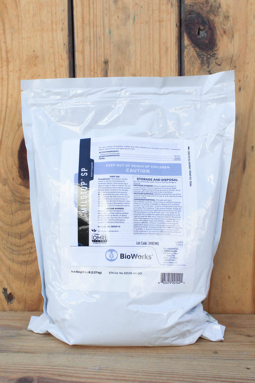 A large white plastic bag of BioWorks Milstop SP standing upright against a rustic wooden plank background.