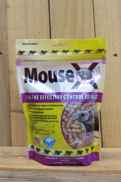 A bag of MouseX rodenticide bait for mice, displayed against a light wood plank background. The packaging is yellow and purple with a clear window showing the brown bait pellets inside.