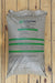 A large bag of Nature Safe Fertilizers 9-0-9 Nitrogen & Potassium Fertilizer, displayed flat on a light-colored wooden plank surface.