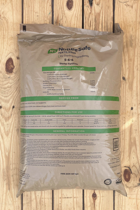 A large bag of Nourisafe Fertilizer 5-6-6 Starter Fertilizer, shown flat on a light-colored wooden plank background.