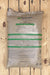 A large bag of NatureSafe Fertilizers Organic & Natural Fertilizer 8-5-5, shown on a light-colored wooden plank background.