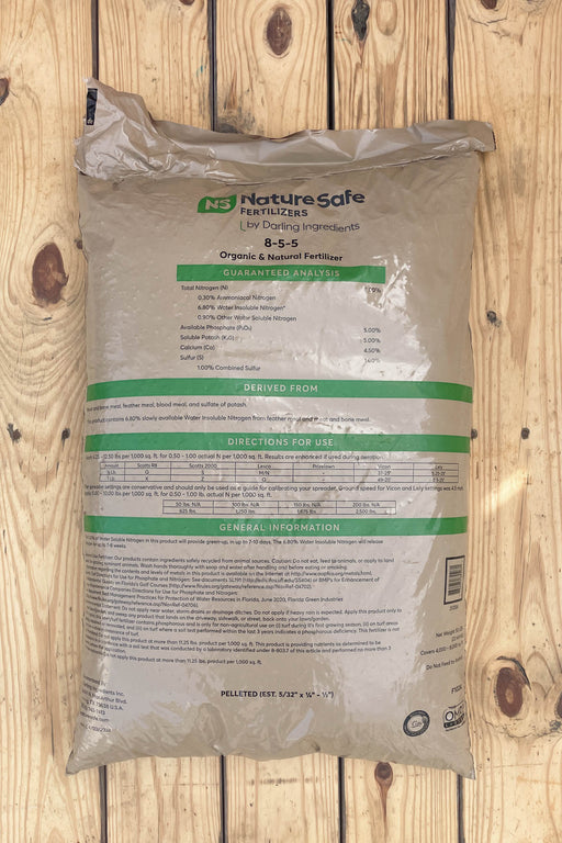A large bag of NatureSafe Fertilizers Organic & Natural Fertilizer 8-5-5, shown on a light-colored wooden plank background.