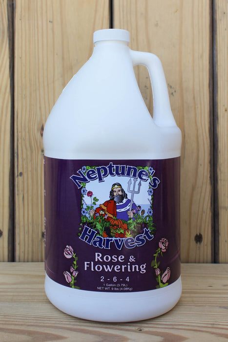 A large white plastic gallon jug of Neptune's Harvest Rose & Flowering fertilizer, featuring a dark purple label with a graphic of Neptune and roses, set against a wooden background.