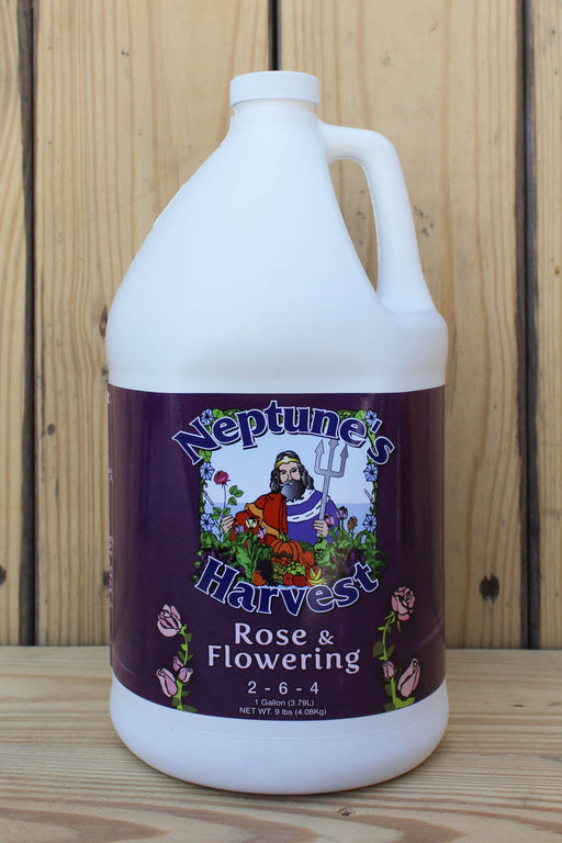 A large white plastic gallon jug of Neptune's Harvest Rose & Flowering fertilizer, featuring a dark purple label with a graphic of Neptune and roses, set against a wooden background.