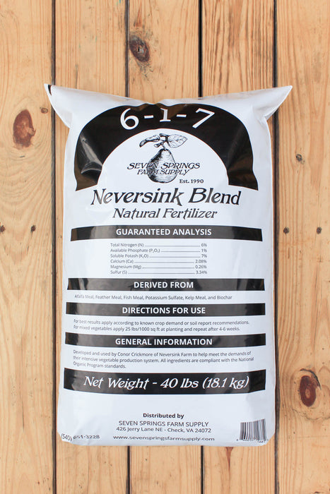 A 40 lb bag of Seven Spring Farm Supply Neversink Blend Natural Fertilizer, labeled 6-1-7, standing upright on a light brown wooden plank surface.