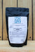 A black resealable pouch of NOFLY Wettable Powder Mycoinsecticide insecticide, featuring a large white label with blue and black text, set against a rustic wooden plank background.
