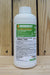 A white plastic bottle of OROBOOST Permanent Spreader-Wetting Aid with a green and white label, set against a rustic wooden plank background.