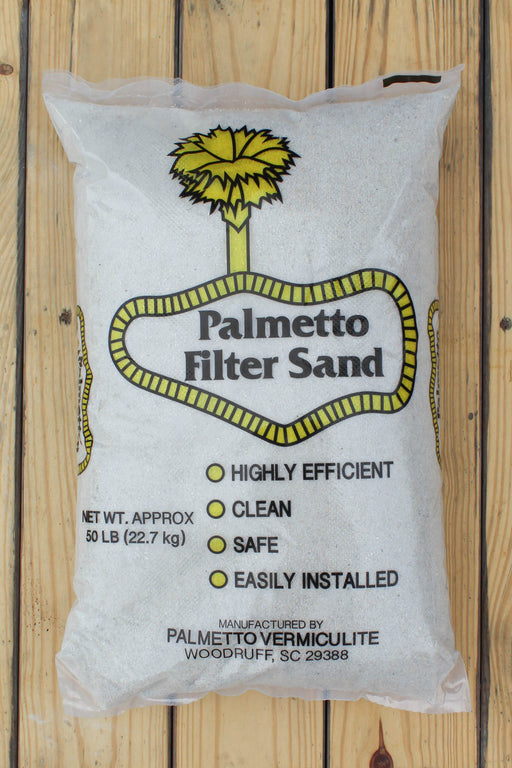 A 50 lb bag of Palmetto Filter Sand on a light wood plank background. The white bag features a yellow palm tree logo and a yellow outlined badge containing the text 'Palmetto Filter Sand'.