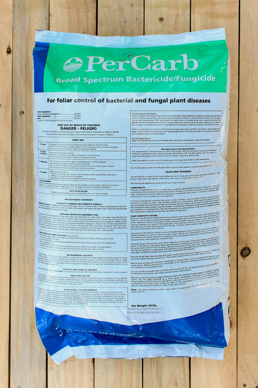 A large plastic bag of PerCarb Broad Spectrum Bactericide/Fungicide, featuring a green and blue header with white text, displayed on a light-colored wooden plank background.