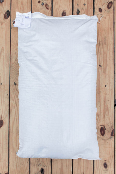 A plain white bag of Peredovik Sunflower seeds laid flat on a light wood plank surface.