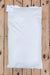 A plain white bag of Peredovik Sunflower seeds laid flat on a light wood plank surface.