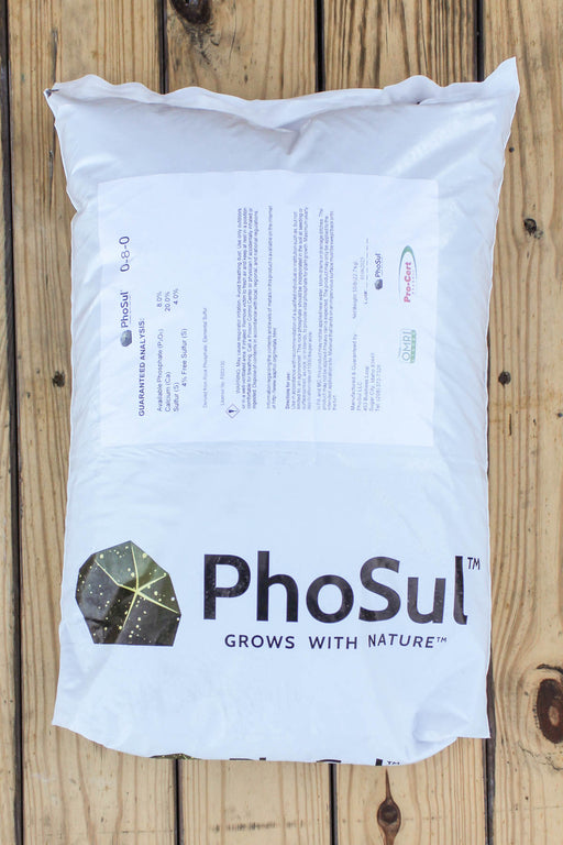 A large white bag of Phosul fertilizer, placed on a light brown wooden plank surface.