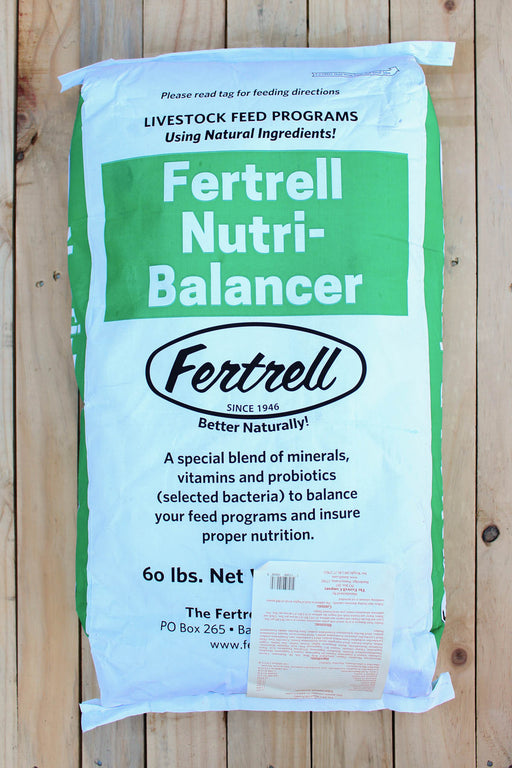 A 60 lb bag of Fertrell Nutri-Balancer livestock feed program supplement, displayed flat on a light-colored wooden plank surface. The bag is white with a prominent green label block and black text.