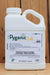 A 1-gallon white plastic bottle of Pyganic 1.4 Crop Protection EC liquid insecticide, standing upright against a vertical wooden plank background.