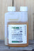 A bottle of PyGanic Gardening with a white cap and a white label, showing the amber-colored liquid inside, set against a rustic wooden background.