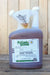 A gallon jug of PyGanic Specialty, featuring a white plastic spout and a translucent brown bottle, set against a rustic wooden plank background.