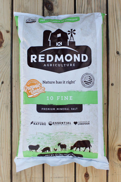 A 50 lb bag of Redmond Agriculture Organic Garlic 10 Fine Premium Mineral Salt, displayed flat on a light-colored wooden plank background.