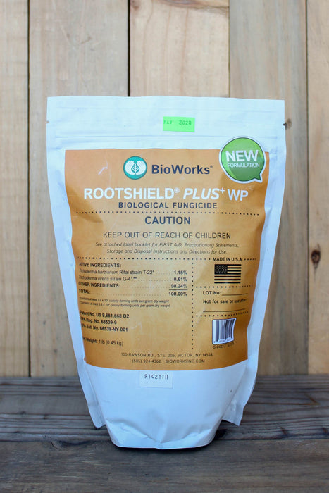 A stand-up pouch of BioWorks Rootshield Plus WP Biological Fungicide, featuring a white bag with a large tan label, photographed against a rustic wooden plank background.