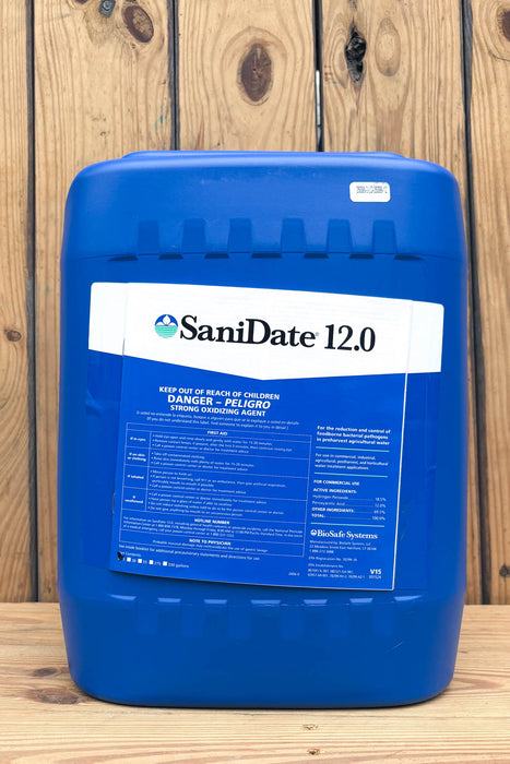A large blue plastic jug of SaniDate 12.0 standing upright against a rustic wooden plank background.