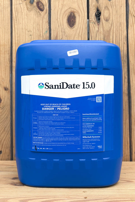 A large blue plastic jug of SaniDate 15.0, standing on a wooden surface against a vertical wood plank background.