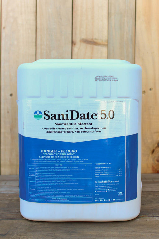 A large white plastic container of SaniDate 5.0 Sanitizer/Disinfectant with a blue and white label, set against a rustic wooden plank background.