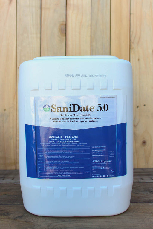 A large white plastic bucket of SaniDate 5.0 Sanitizer Disinfectant with a blue and white label, set against a light wood panel background.