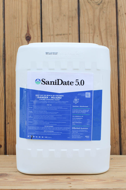 A large white plastic bucket of SaniDate 5.0, featuring a blue and white label, set against a rustic wooden plank background.